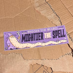 May include: A rectangular sticker with a purple background featuring a wizard in a purple robe holding a staff. The wizard has an extremely long, flowing cream-colored beard. The text reads: THE BIGGER THE BEARD, THE MIGHTIER THE SPELL.