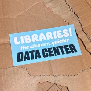May include: A rectangular light blue sticker featuring the white text LIBRARIES! in a bold font, followed by the smaller white text the cleaner, quieter, and the large black text DATA CENTER. A small website URL is printed in the bottom right corner.