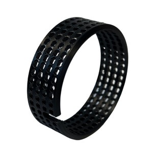 May include: A black, flexible band with a series of perforations, possibly rubber or a similar material. The band is curved, featuring multiple rows of evenly spaced holes. The material has a matte finish, and the shape suggests it could be a component or accessory.