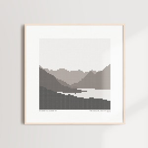 Puede incluir: Una impresión enmarcada en blanco y negro de un paisaje pixelado que representa una cordillera y un lago. La impresión se titula "The Golden Hour, 18.10.2019" y tiene las coordenadas "51.0083° N, 4.3683° E" impresas debajo de la imagen.