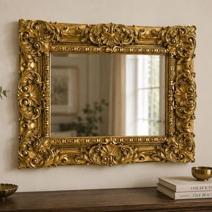 Può includere: Uno specchio da parete rettangolare con un'ampia cornice dorata decorata, caratterizzata da complessi motivi a volute, disegni floreali e intagli a forma di conchiglia al centro di ogni lato. La superficie riflettente mostra la stanza.