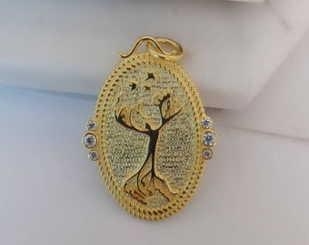 May include: A gold oval pendant with a tree design and small clear stones around the edge.