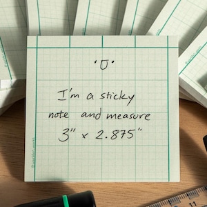 May include: Stacks of graph paper sticky notes with green grid lines, a ruler, and a pen. The central note reads: "I'm a sticky note and measure 3" x 2.875". A black and green screwdriver is also present.