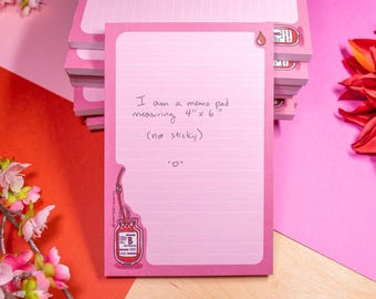 May include: Pink memo pads with lined pages. Each pad measures 4" x 6" and features a blood bag illustration and the text "I am a memo pad measuring 4" x 6" (not sticky)." A stack of pads is visible.