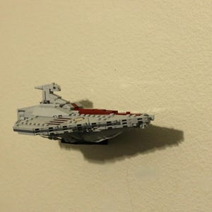 May include: A white and red Lego Star Wars spaceship model with a gray cockpit and a red stripe on the side.