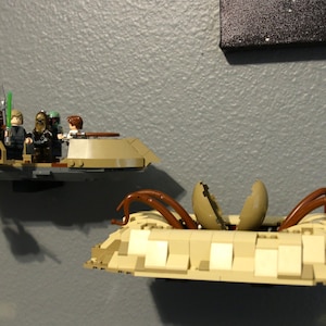 May include: A Lego spaceship with a crew of minifigures, including a pilot, a passenger, and a droid. The spaceship is brown and tan with a green stripe. The spaceship is flying over a sand-colored landscape.