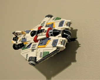 May include: A white, yellow, blue, green, and red Lego spaceship with a black cockpit.