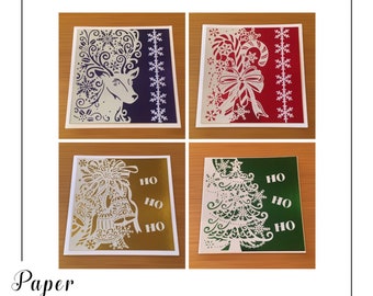 Puede incluir: Cuatro tarjetas de Navidad cortadas en papel con diferentes diseños. La primera tarjeta presenta un ciervo blanco con un fondo morado. La segunda tarjeta presenta un bastón de caramelo blanco y un lazo con un fondo rojo. La tercera tarjeta presenta campanas blancas con un fondo dorado. La cuarta tarjeta presenta un árbol de Navidad blanco con un fondo verde.