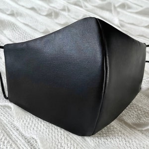 Puede incluir: Una mascarilla facial negra hecha de un material liso y brillante. La mascarilla tiene dos cintas el&aacute;sticas para llevarla.