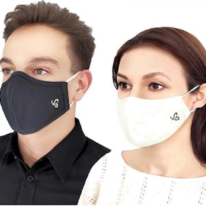 May include: Two people wearing face masks. The person on the left is wearing a black face mask with a small gold logo. The person on the right is wearing a white face mask with a small gold logo.