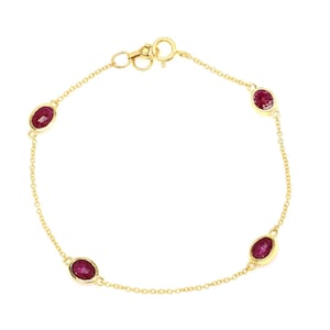 Op de afbeelding: Een delicate gouden armband met vier ovaalvormige, dieprode edelstenen. De edelstenen zijn gelijkmatig verdeeld over een fijne gouden ketting, met een veilige sluiting. De armband is ontworpen voor dagelijks gebruik en voegt elegantie toe.
