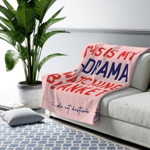 May include: Pink throw blanket with the text "This is my drama watching blanket...  do not disturb" in red, blue, and white lettering. A heart with a finger pointing to the left is at the bottom right corner.