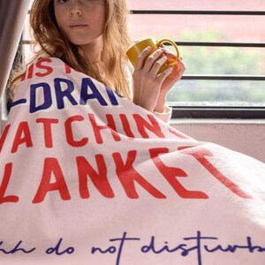 May include: Pink throw blanket with the text "This is my drama watching blanket... shh do not disturb" in red, blue, and white lettering.
