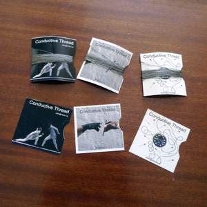 Pode incluir: Seis cartões com o texto "Conductive Thread" impresso neles. Cada cartão apresenta uma imagem diferente, incluindo um par de esgrimistas, duas mãos se tocando, uma mão segurando uma agulha e uma placa de circuito com fio condutor.