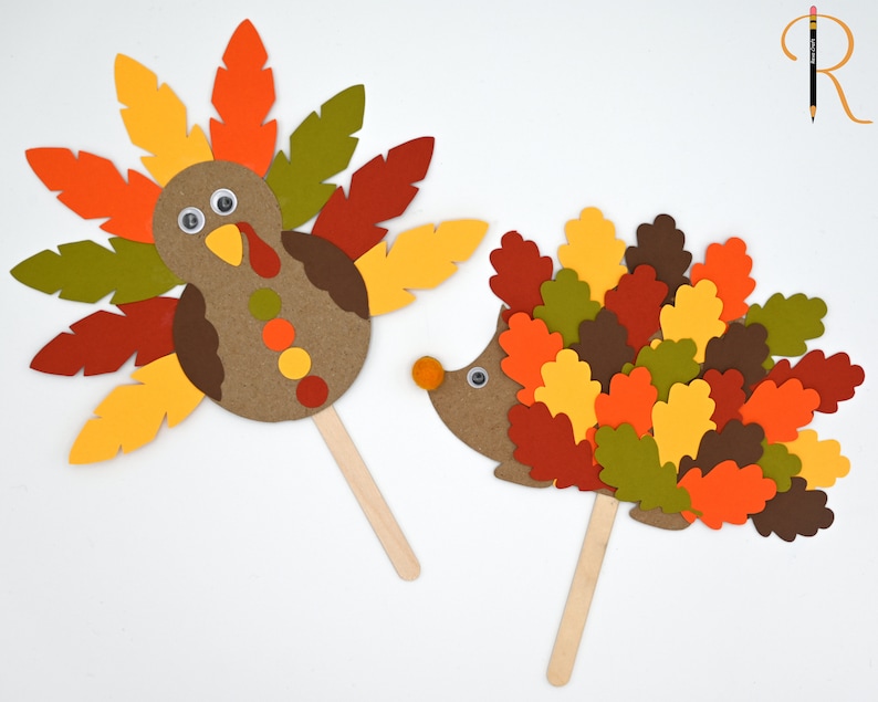 May include: Two paper craft puppets on sticks. One is a turkey with brown, red, yellow, and green feathers. The other is a hedgehog with brown, red, yellow, and green leaves for quills.