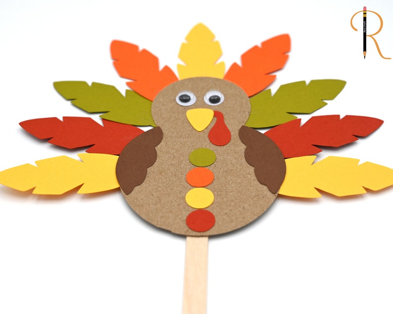 May include: A paper craft turkey with brown, orange, yellow, and green feathers. The turkey has a brown body with a yellow beak, red wattle, and googly eyes.