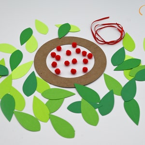 May include: A craft project with a brown paper circle, red pom-poms, and green paper leaves.