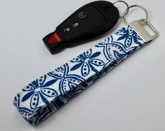 May include: A white and blue patterned key chain with a silver key ring and a black car key fob with a red "PANIC" button.