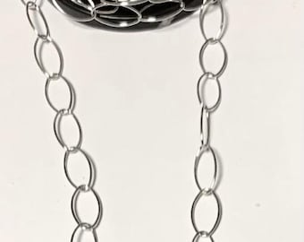 May include: A spool of silver oval chain, with a section of the chain hanging down.