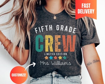 May include: A dark heather grey t-shirt with the text "FIFTH GRADE CREW LIMITED EDITION Mrs. Williams" in a vintage style with colorful lettering and stars.