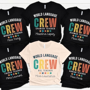 May include: A collection of black and cream-colored t-shirts with the text "WORLD LANGUAGE CREW" in a colorful design. Each shirt is customized for different language teachers, including Mandarin, Spanish, German, French, ASL, and Korean.