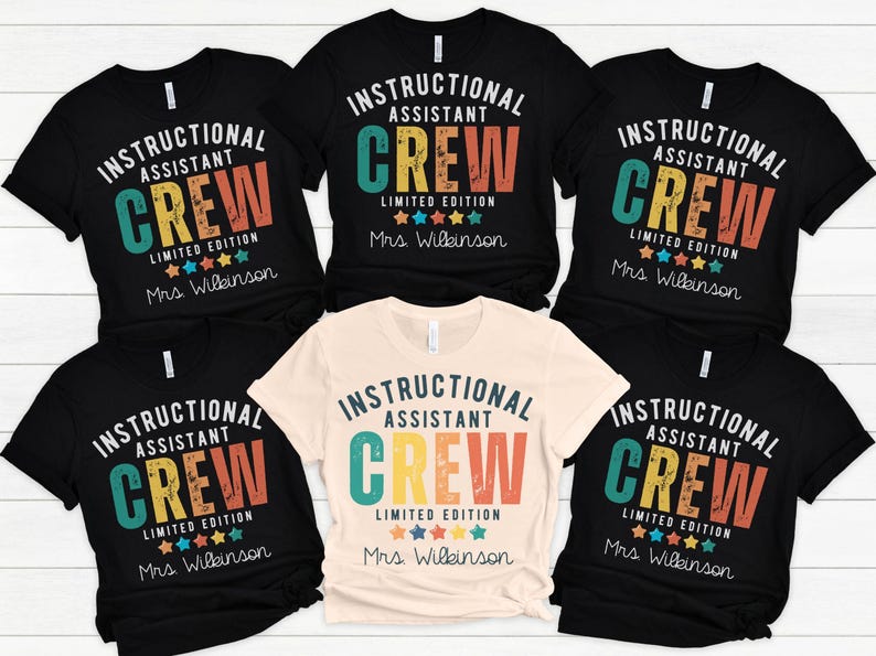 May include: Several black and cream t-shirts are displayed, each bearing the text "INSTRUCTIONAL ASSISTANT CREW LIMITED EDITION" in a vintage style. The shirts have a round neckline and short sleeves. The name "Mrs. Wilkinson" is printed below.