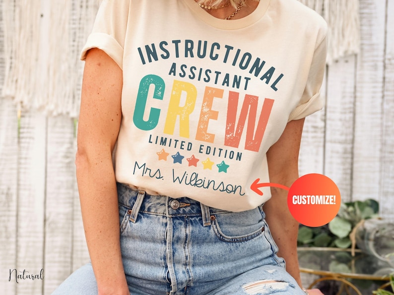 May include: A cream-coloured t-shirt featuring the text "INSTRUCTIONAL ASSISTANT CREW" in a retro font. Below the text are the words "LIMITED EDITION" and a row of stars. The name "Mrs. Wilkinson" is printed below the stars.