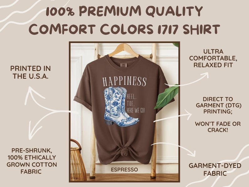 May include: Espresso-coloured t-shirt with a watercolour design of a blue and white cowboy boot. The shirt features the word "Happiness" and the phrase "Heel Toe Here We Go!" printed on the front. The shirt is made of garment-dyed, pre-shrunk cotton.