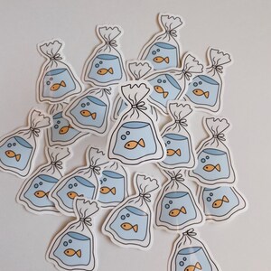 May include: A collection of stickers featuring a cartoon goldfish in a plastic bag. The stickers are white with blue and orange accents.