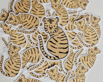 May include: A collection of 20+ tiger stickers, each featuring a simple line drawing of a tiger in a sitting position. The tigers are all facing forward and have a similar expression. The stickers are all white with black outlines and are printed on a clear background.