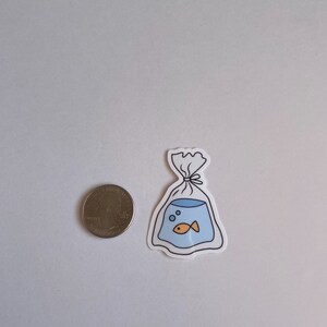 May include: A white sticker with a black outline of a plastic bag with a goldfish inside. The goldfish is orange and there are two blue bubbles in the bag.