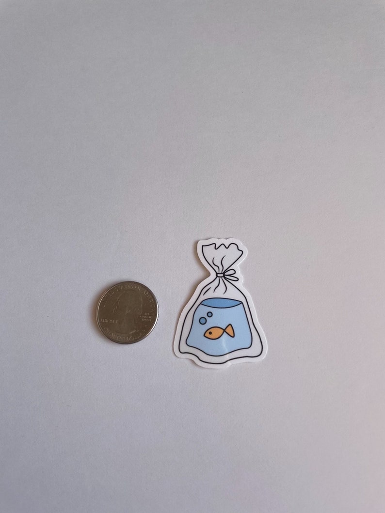 May include: A white sticker with a black outline of a plastic bag with a goldfish inside. The goldfish is orange and there are two blue bubbles in the bag.