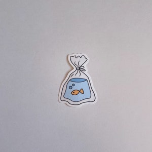 May include: A white sticker with a black outline of a plastic bag with a blue fishbowl inside. The fishbowl has a small orange fish and bubbles inside.