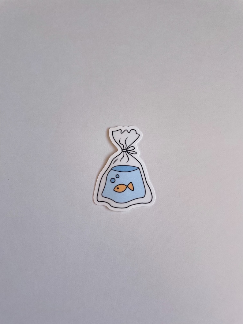 May include: A white sticker with a black outline of a plastic bag with a blue fishbowl inside. The fishbowl has a small orange fish and bubbles inside.