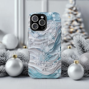 May include: A smartphone case featuring a layered, wavy design in shades of light blue, white, and gray. The surface is decorated with various white snowflake patterns of different sizes, creating a textured, three-dimensional appearance.