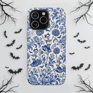 May include: A smartphone case featuring a blue and white toile-style pattern with skeletons dressed as cheerleaders holding pom-poms, interspersed with pumpkins, spiderwebs, and bats against a cream-colored background.