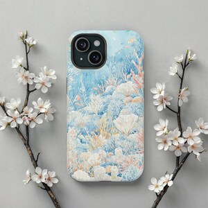 May include: A phone case with a watercolor design of coral reefs in shades of blue, pink, and white. The case has a camera lens cutout and a white background.