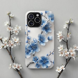 Puede incluir: Una funda blanca para iPhone con un diseño floral con flores azules y hojas verdes. La funda tiene la parte posterior transparente y un borde blanco.