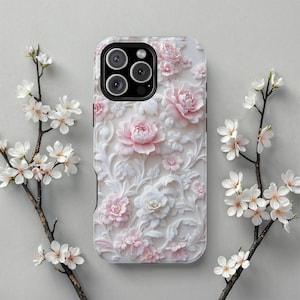 May include: A white phone case with a 3D floral design featuring pink and white roses and other flowers. The case has a black camera module and is surrounded by branches with white flowers.