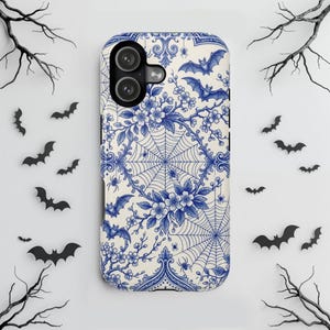 May include: A rectangular smartphone case featuring a blue and white pattern of floral branches, spiderwebs, spiders, and flying bats. The design mimics traditional porcelain aesthetics with intricate linework on a cream-colored background.