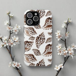 May include: White phone case with a repeating pattern of brown and tan seashells. The case has a glossy finish and a camera cutout. The design includes various shell shapes and sizes, creating a coastal theme.