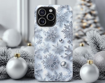 May include: A white phone case with a silver snowflake pattern. The case has a camera module with three lenses. The background includes Christmas ornaments and a decorative tree, creating a festive holiday theme.