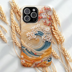Puede incluir: Una funda de teléfono con un diseño de inspiración japonesa, que presenta una ola, flores de cerezo y un árbol con hojas rojas y amarillas. La funda tiene una combinación de colores beige, azul y naranja.