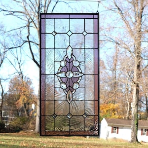 May include: A rectangular stained glass window with a black frame and a decorative design. The window features a central purple and clear glass design with diamond and oval shapes. The background glass has a textured appearance.