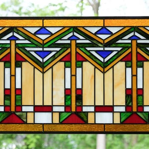 May include: Rectangular stained glass panel with a geometric design. The panel features a gold border, with a pattern of green, blue, red, and white shapes. The central design includes vertical and horizontal lines.