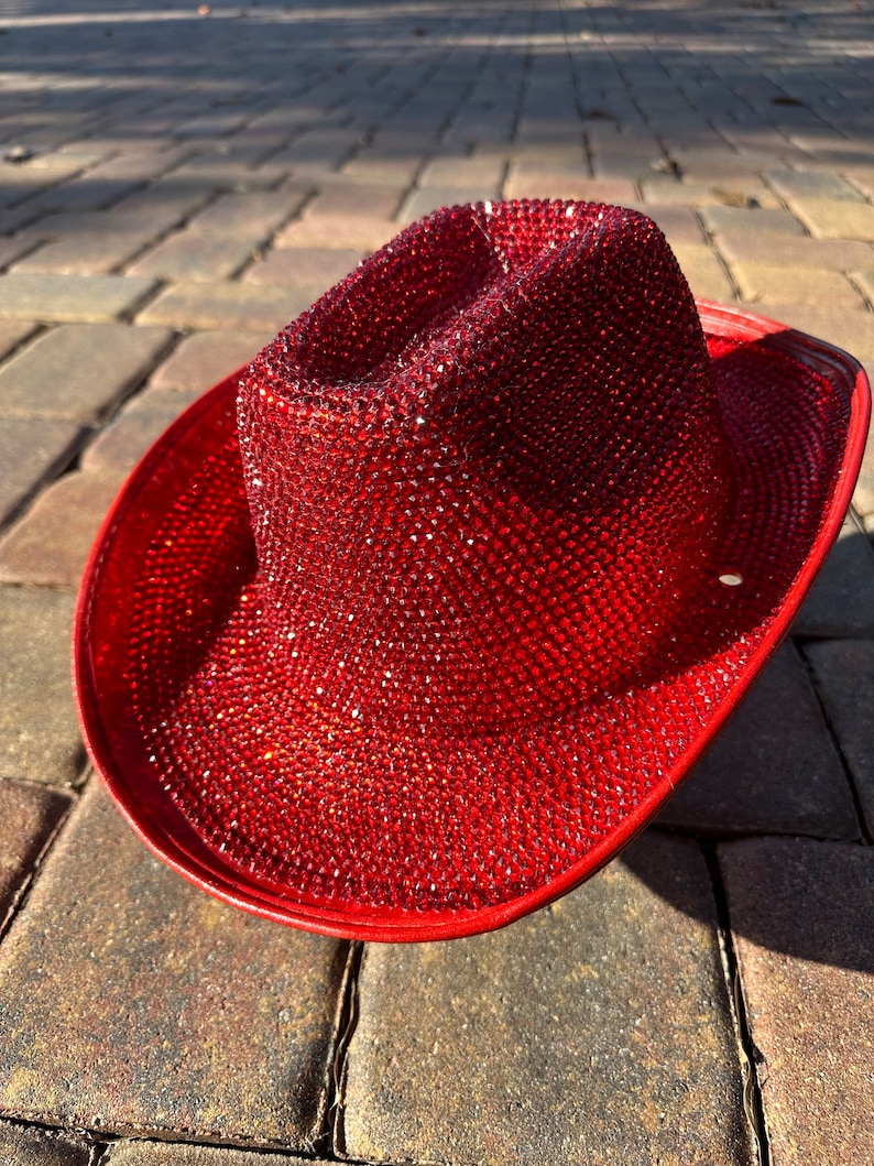 K&ouml;nnte beinhalten: Ein roter Cowboyhut, der mit funkelnden roten Strasssteinen besetzt ist.