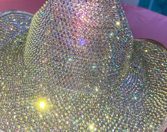 May include: A white cowboy hat completely covered in iridescent rhinestones.