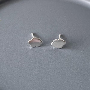May include: A pair of silver cloud-shaped stud earrings. The earrings are small and delicate, and they would make a great gift for a friend or loved one.
