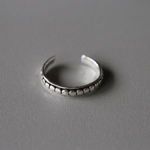 May include: A silver toe ring with a textured band of small, round beads.