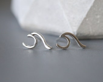 May include: A pair of silver wave-shaped stud earrings. The earrings are small and delicate, and they would make a great gift for someone who loves the ocean.